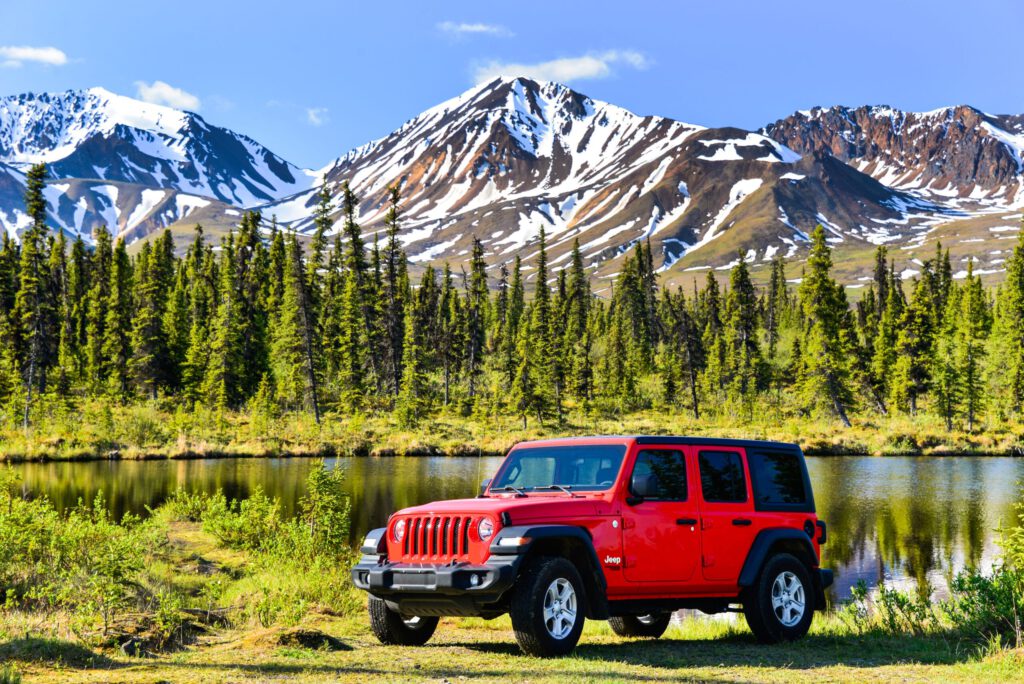 A Jeep is parked off the Denali Highway near a lake.