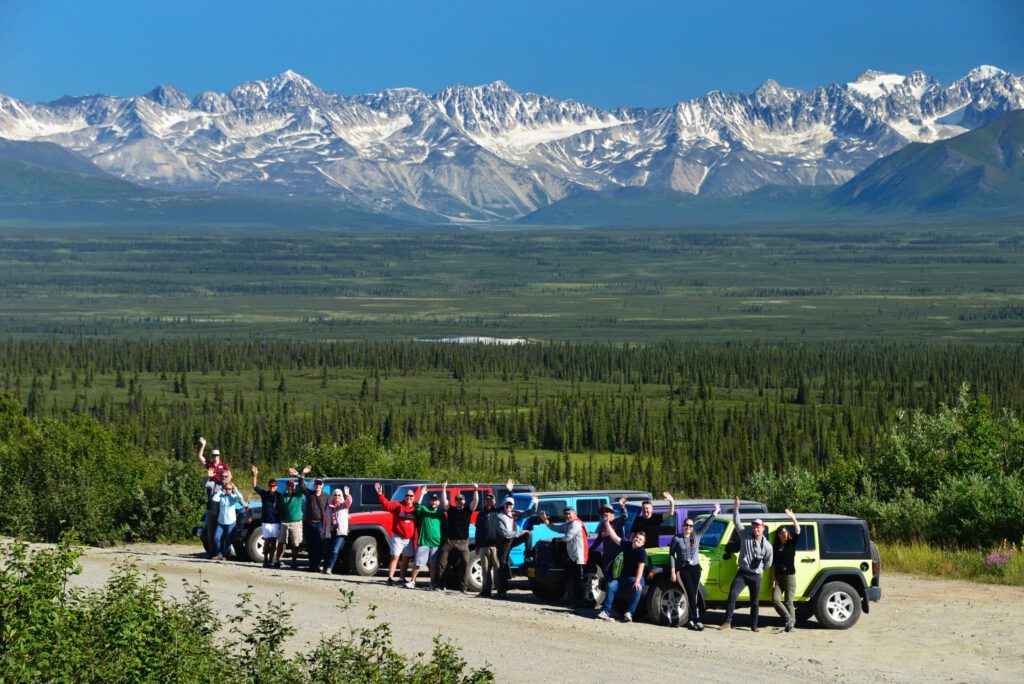 A Jeep tour stops to take pictures and waves in a group picture.