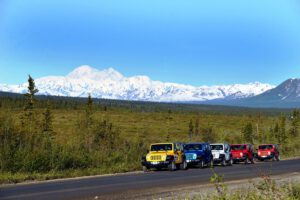 A Jeep tour parks on the Denali Highway to take pictures of Denali.