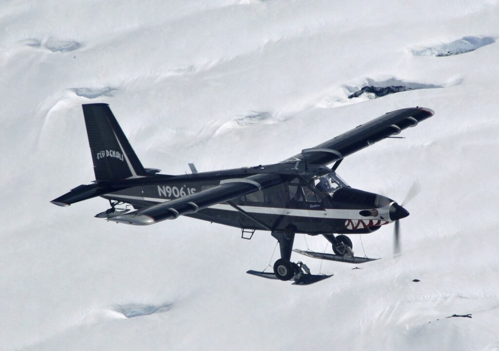 A plane flies over a snowy mountain.