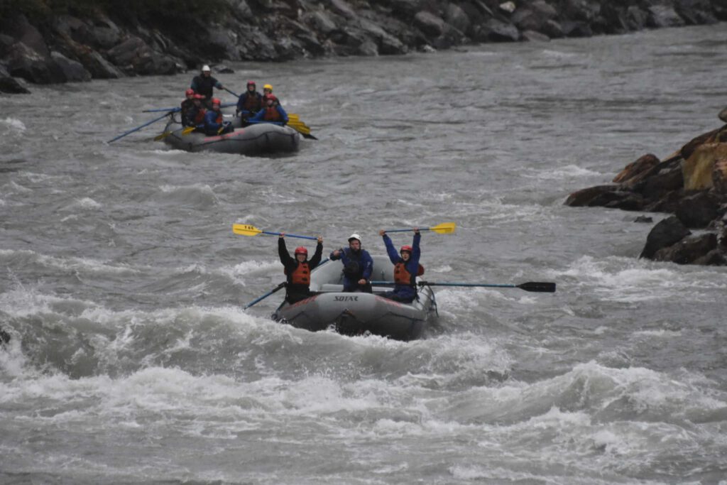 Rafters raise their oars in celebration of conquering the Nenana River whitewater.