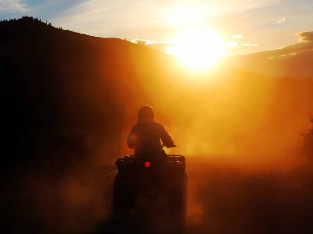 A silhouette of a single ATV rider against the Midnight Sun.