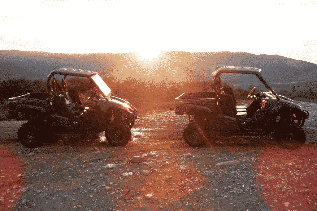 Two ATVs on the trail framed against the sun.