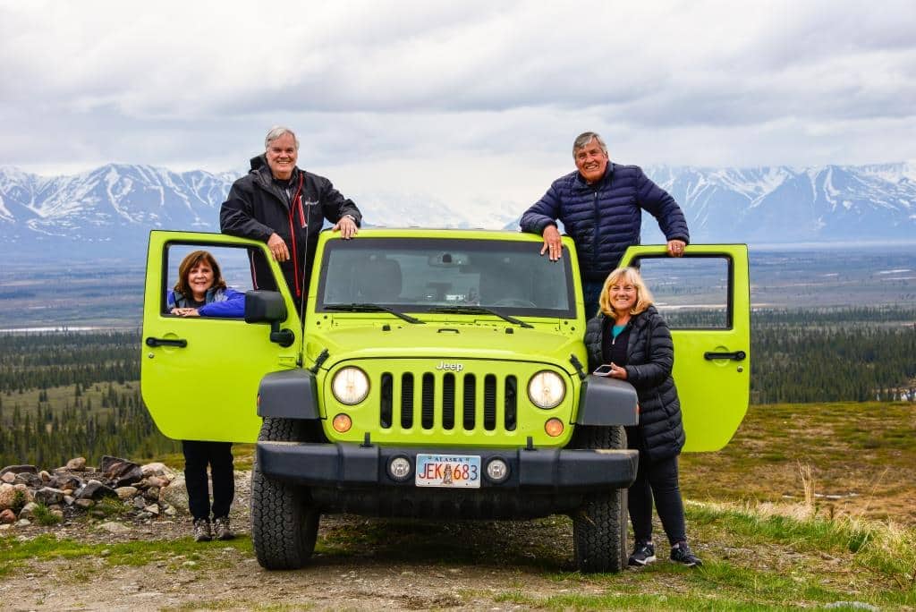 Two couples pose by a Jeep while out on the Denali Highway.