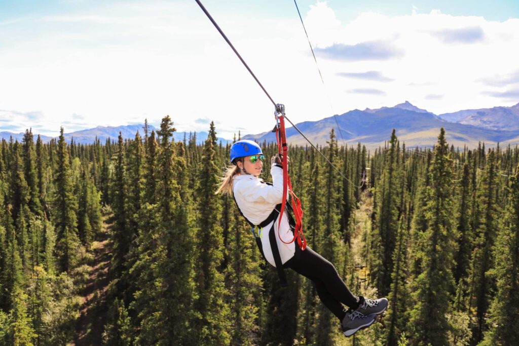 Woman flies above the boreal forest on zipline.