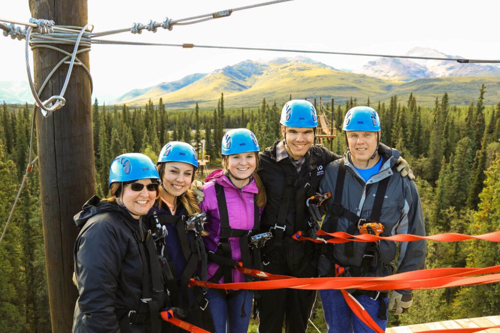 A zipline group poses above the boreal forest.