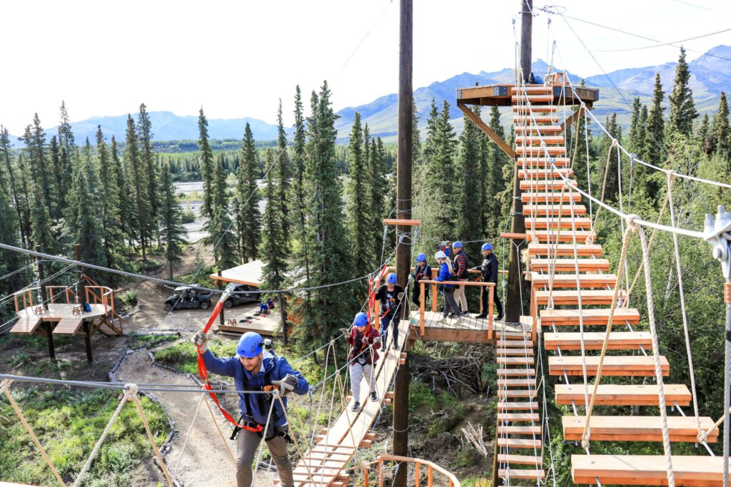 A zipline tour crosses a suspension bridge on a Denali Park Zipline tour.