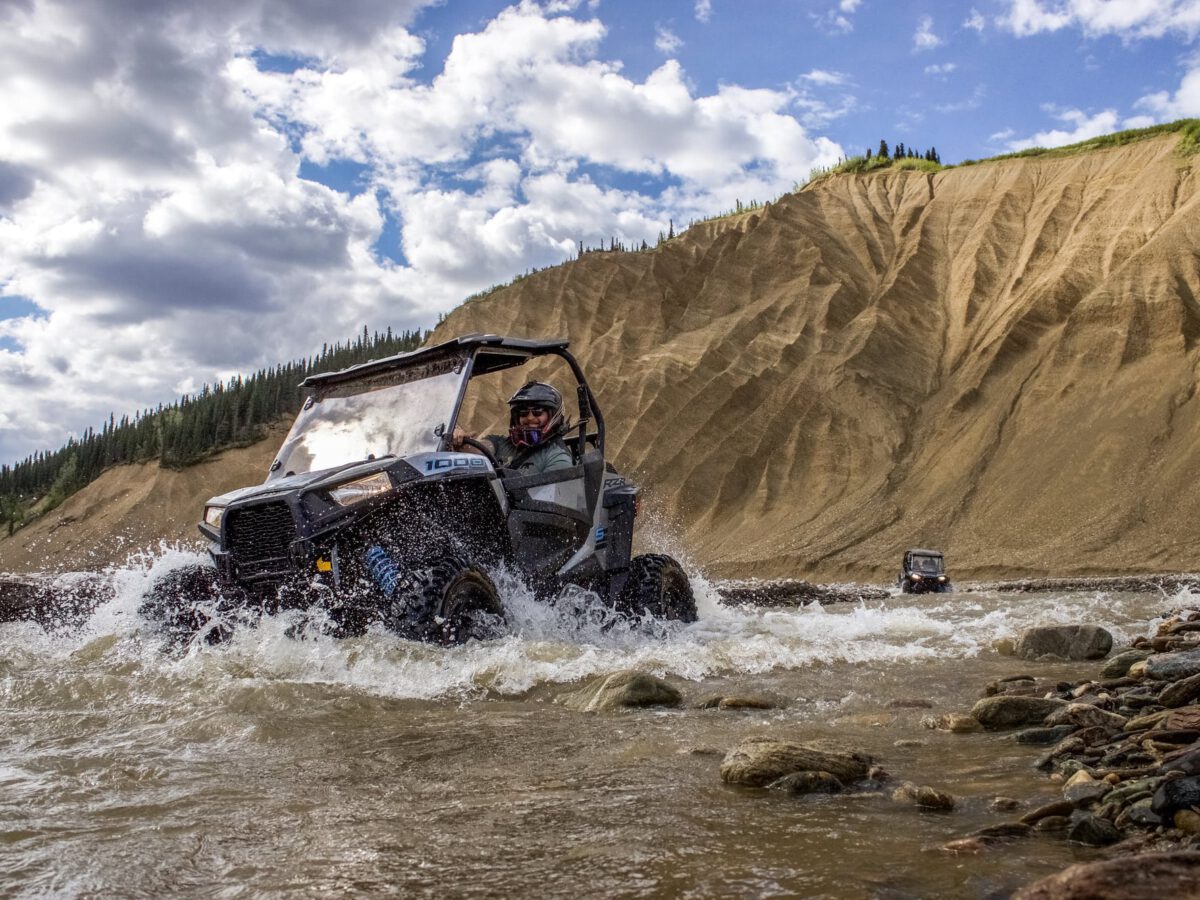 An ATV splashes through a stream on the trail in Denali.